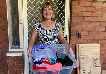 Resident with box of textiles, e-waste and cardboard for home pick-up recycling