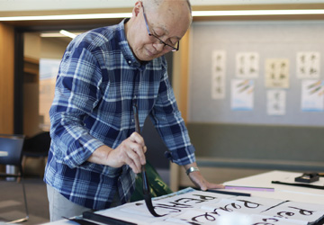 A Korean man does calligraphy in The Learning Space