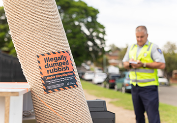 Image of some illegally dumped items with a ranger in the background