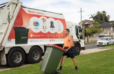 Man pushing bin in front of waste truck
