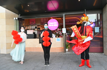 Image of asian woman dressed as moon fairy, with shopkeeper and asian man dressed as the Chinese God of Wealth, all holding lanterns. 
