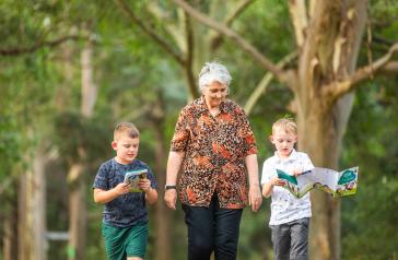Children with their grandmother walking along the tree trail with the trail guide