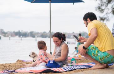 Family sitting on sand at Bayview Park Baths