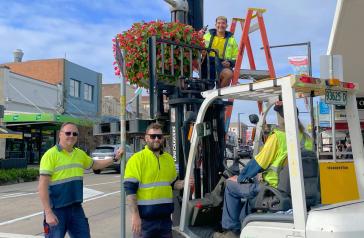 Council staff in front of flower baskets on Great North Road
